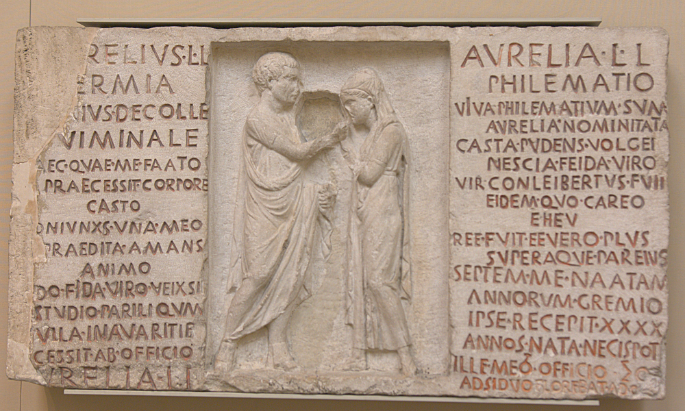 Marble tombstone with relief of two figures in the centre, with an inscription either side
