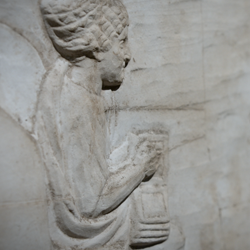 Stone engraving of a woman seated with wax tablets